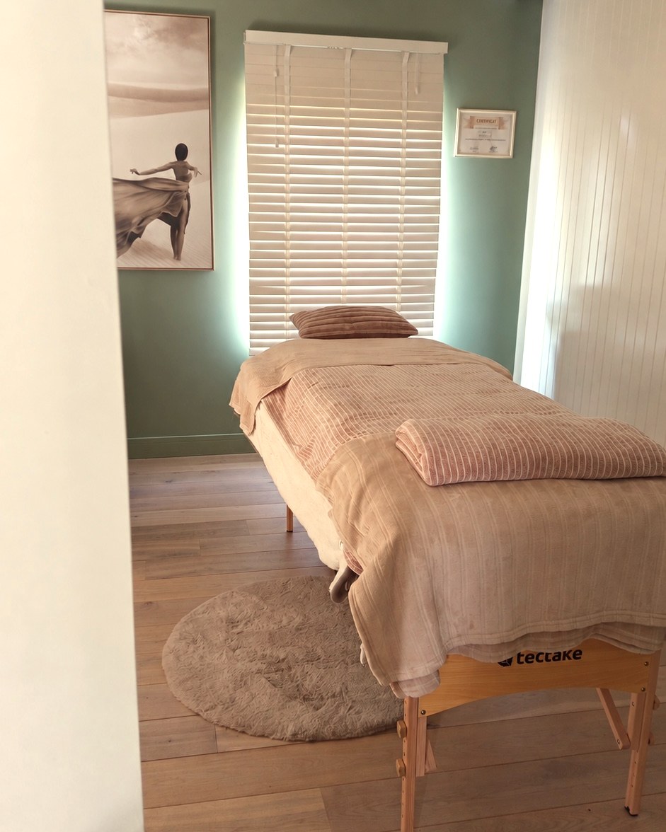 La cabine de soin de l’institut Ambréa, à Merdorp : table de massage dressée devant les stores en bois