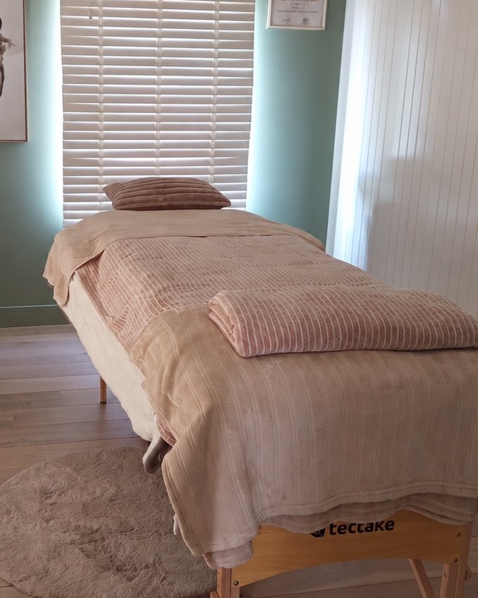 La table de massage dressée devant la fenêtre à stores