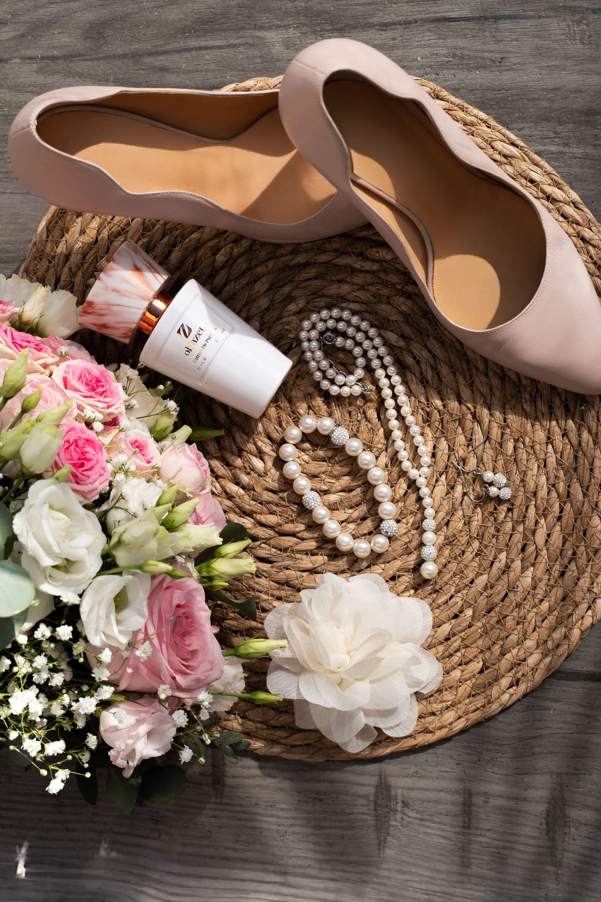 Flacon Olfazeta blanc présenté avec un bouquet de mariée et des perles